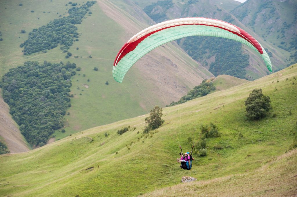 paraglider lands in the mountains in summer. paragliding training